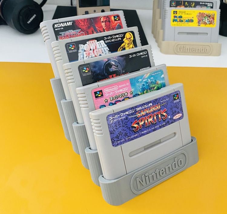 Présentoir RetroPixy exposant cinq cartouches Super Famicom en gradins sur un bureau jaune
